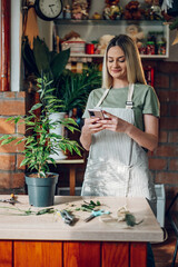 Woman florist using a smartphone while working in a flower shop