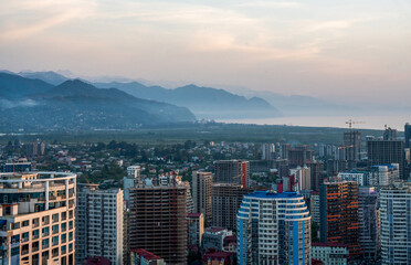 Suburbs of Batumi with skyscrapers in sunset and amazing mountain range in tonal perspective