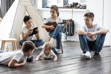 Fototapeta premium Five kids at home in the living room playing games