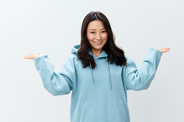 Cheerful happy cute Asian young female in blue hoodie sweatshirt holds invisible objects on palms...