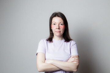 Fototapeta premium beautiful girl makes a cosmetic procedure. The girl uses eye patches. the woman crossed her arms over her chest. Pose of distrust