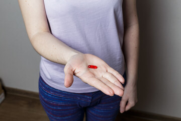 girl holding a red pill in her hand