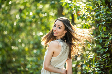 A beautiful happy teenage brunette girl outdoors in a wooded area in the spring spinning around