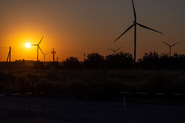 Concept of environmental conservation and climate change. Clean wind energy against backdrop of setting sun and poles with wires, alternative clean energy.