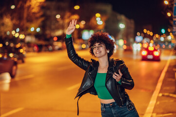 Woman calling a taxi while standing on road in city