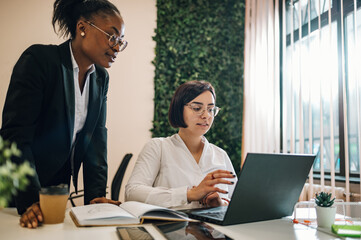 Two multiracial businesswoman working together in an open space office