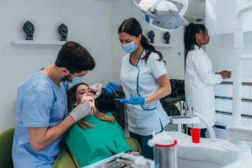 Woman patient in dental clinic being examined by a male dentist