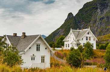 Fototapeta na wymiar Lofoten Islands, classic norwegian landscape, small houses of white color on the coast, rocky coast with dramatic sky
