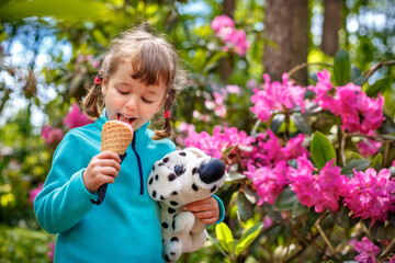 Adorable little girl eating tasty fresh ice cream and holding dog toy - 502481845