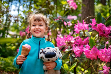 Adorable little girl eating tasty fresh ice cream and holding dog toy - 502481846