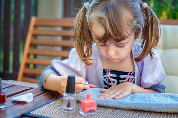 Adorable little girls having fun playing at home with nail polish doing manicure