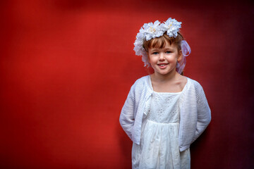 Adorable little girl wearing flower crown and posing on red background outdoors - 502481868