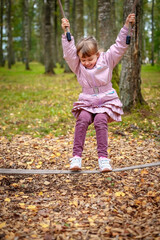 Cute happy little girl plays outdoors at playground on warm sunny autumn day