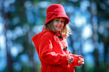 Cute happy little girl wearing red retro hat and coat posing in city park - 502481875