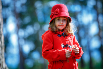Cute happy little girl wearing red retro hat and coat posing in city park - 502481880