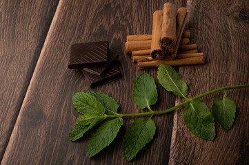 chocolate, mint and cinnamon on a dark wood background