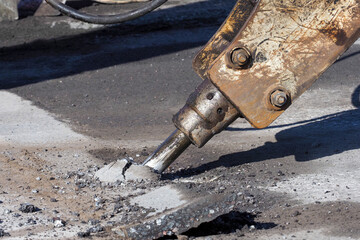 Jackhammer has been drilled into the asphalt road. Machine drills asphalt. Repairing driveway...