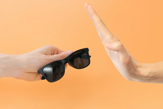 Man refusing to take a black sunglasses on an orange background. Arm. Protect. Relax. Fashion. Holiday. Lifestyle. Elegance. Lens. Trend. Eyeglasses. Classic. Products