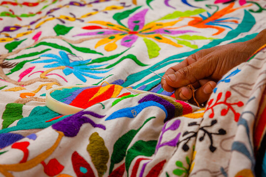 Close up photo of hand-weaving a multicolored Tenango, one of the traditional fabrics of Mexico, in the process of embroidery.