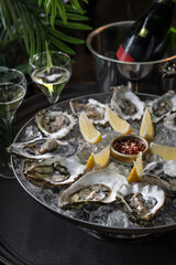 Fresh oysters on a platter in ice with a slice of lemon and spicy sauce.