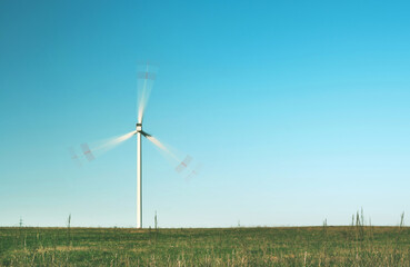 Fototapeta premium moving lone wind turbine in green field