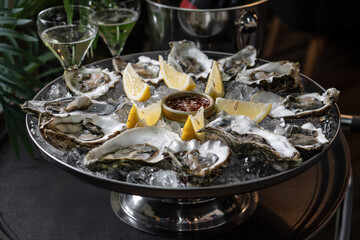 Fresh oysters on a platter in ice with a slice of lemon and spicy sauce.