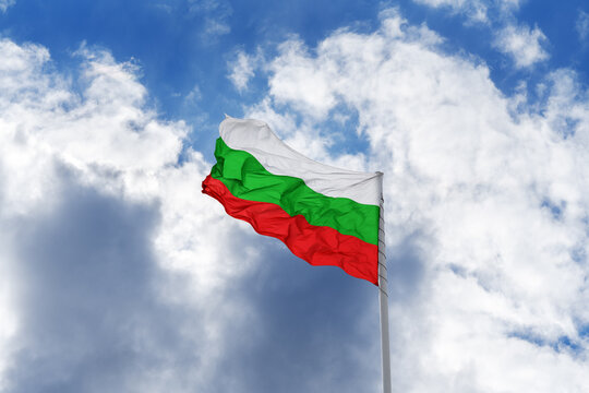 Flag of Bulgaria is waving in front of blue sky and clouds