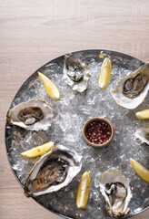 Fresh oysters on a platter in ice with a slice of lemon and spicy sauce.
