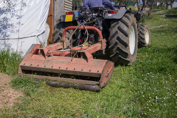 Obraz premium Farmer driving a tractor in the countryside while cutting the grass with a forage harvester