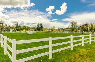 Fototapeta na wymiar Typical white wooden fence in farmland. Spring in rural area.