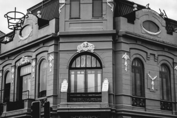 Beautiful windows and balconies in a old centuries building with neoclassical architecture, ornaments and sculptures in a cloudy day, Valdivia, Chile (in black and white)