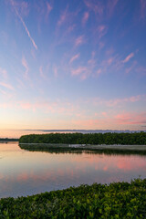 Sunset over still water with birds silhouetted in background