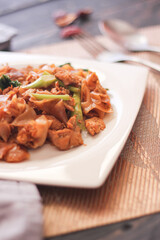 Stir fried Noodle with black soy sauce served in a white plate. on the black wooden table or what we call 