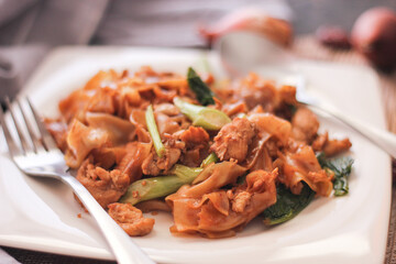 Thai Soy Sauce Fried Noodles served in a white plate. on the black wooden table or what we call 