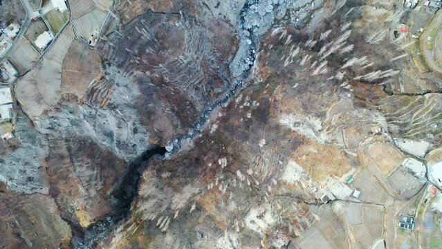 Aerial Panning Directly Over A River Canyon And The Edge Of A Remote Mountain Village - Hunza Valley, Pakistan
