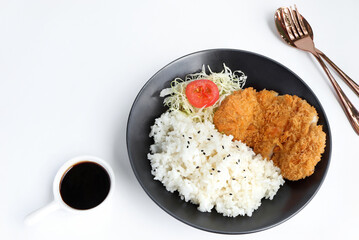 Tonkatsu taken serve with rice. Pork cutlet and shredded cabbage on a black plate on white table. japanese food style