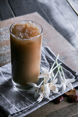 Iced coffee on a leaf-shaped placemat with white flowers.