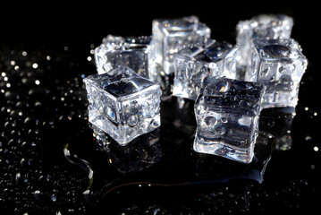 Crystal clear ice cubes with water drops reflection isolated on black background. 