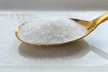 Close up of monosodium glutamate, MSG on a spoon on white background. 