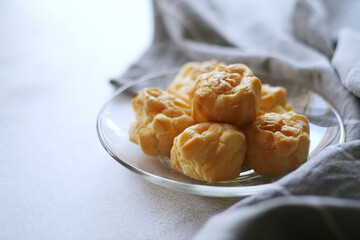 The eclair is placed in a glass dish on a white table.