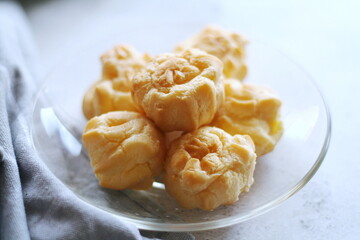 The eclair is placed in a glass dish on a white table.