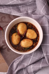 Egg with Tamarind Sauce in a white plate served on a wooden table with coriander sprinkles, is a popular local dish that Thai people eat.