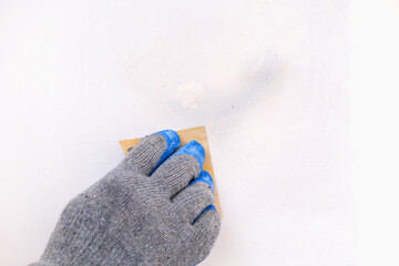 A man cleans old paint on a wooden door with sandpaper. Smoothing out irregularities.