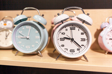 Round alarm clock on the store shelf close-up. Sale of various watches and alarm clocks of different colors. Retro alarm clock on the table, vintage tone.