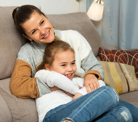Fototapeta na wymiar Happy woman laughing and tickle her daughter in home interior