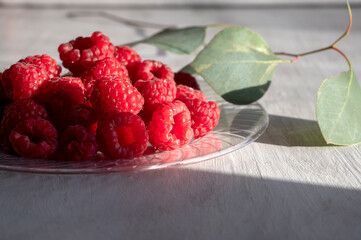 delicious raspberries on plate with green leaves next to it 
