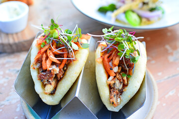 A pair of healthy, tasty gourmet Korean tacos with a bao bun at a hip urban restaurant