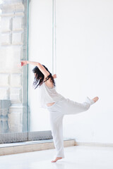 Young woman in white clothes dancing in a studio