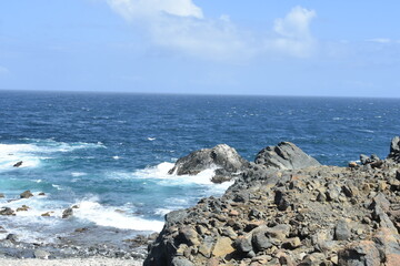 rocky ocean shoreline with rough water and an island