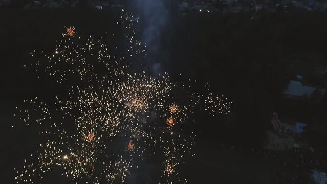 Aerial view of Fireworks at the Village stadium in the night. Stadium in the forest on the outskirts of the village. Lightning flashes on the sky, a thunderstorm begins. Around you can see houses, for